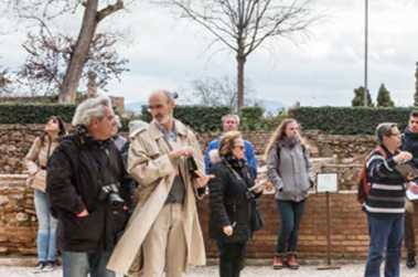 Fotografía de los alrededores de una edificación antigua con un grupo de personas escuchando a un guía turístico.