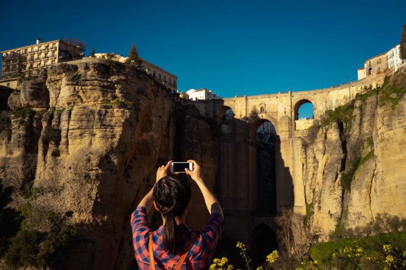 Mujer de espaldas haciendo una fotografía a un enclave turístico.